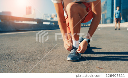 Person, hands or tying shoes in city street for fitness preparation, workout or exercise. Closeup, active or runner getting ready with tie or laces on road for cardio training, sprint or race in town 126407811