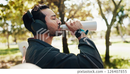 Break, drinking water and music with man in park for exercise, fitness or running routine. Headphones, hydration and streaming with athlete or runner outdoor in nature for recovery, relax and rest Break, drinking water and music with man in park for exercise, fitness or running routine. Headphones, hydration and streaming with athlete or runner outdoor in nature for recovery, relax and rest 126407855
