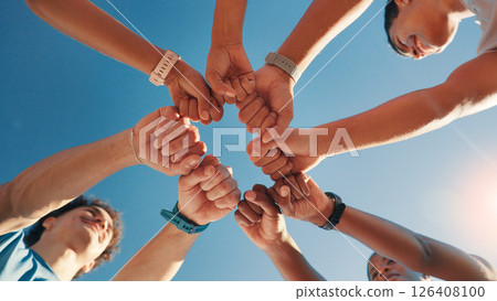 People, team and fist bump in fitness with blue sky below for motivation, unity or mission. Low angle, group or friends with hands together in huddle, circle or solidarity for health and wellness 126408100