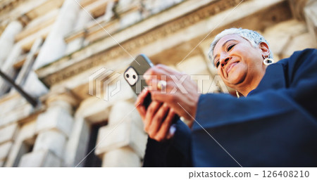 Cellphone, lawyer and businesswoman in city with communication, contact or email with legal client. Phone, research and female attorney with online networking for legislation case in town from below. 126408210