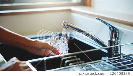Glass, hands and water with person in kitchen of home for health, hydration or wellness closeup. Drink, faucet and thirsty with woman at sink in apartment for beverage or natural refreshment Glass, hands and water with person in kitchen of home for health, hydration or wellness closeup. Drink, faucet and thirsty with woman at sink in apartment for beverage or natural refreshment 126408329