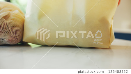 Grocery bag, recycling symbol and shopping on kitchen counter for eco friendly conservation. Ecology, reusable and sustainability with groceries closeup in apartment for consumerism or zero waste 126408332