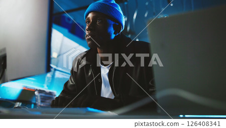 Black man, hacker and reading on computer at night for programming, cyber attack and online information. Male person, pc and research for website phishing, data protection and criminal for fraud risk 126408341