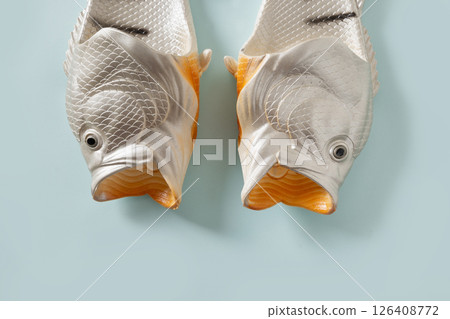 Rubber slippers shaped of fish. Fishermen slippers for beach on blue background. Summer vacation. Creative funny flip flops. View from above. Rubber slippers shaped of fish. Fishermen slippers for beach on blue background. Summer vacation. Creative funny flip flops. View from above. 126408772