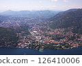 Aerial view of Como city and Lake Como, surrounded by lush hills and mountains, with boats on the water and scenic urban landscape in northern Italy. 126410006