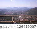 Aerial view of Como city, surrounded by lush hills and mountains, scenic urban landscape in northern Italy. Rusty railings with lock in the foreground 126410007