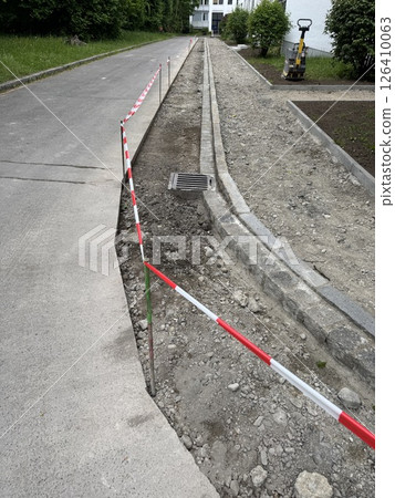 Road is being repaired and a red and white striped barrier is in place 126410063