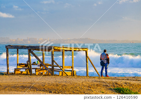 Male person relaxing on seashore, looking at waves Male person relaxing on seashore, looking at waves 126410590