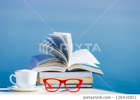 Coffee cup, book and glasses against blue sea. Coffee cup, book and glasses against blue sea. 126410851