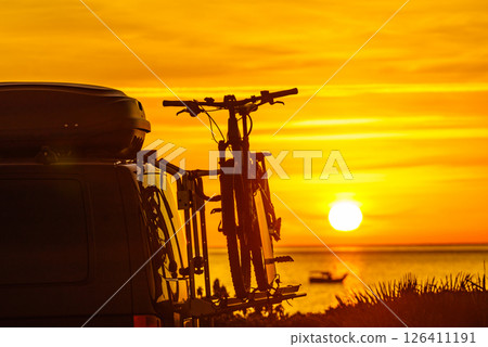 Camper with bicycles on rack camping on beach at sunrise 126411191