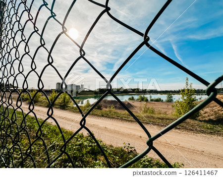 A chain link fence with a view of a lake and a building in the background 126411467