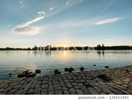 Beautiful sunset over a body of water with a few ducks in the water Beautiful sunset over a body of water with a few ducks in the water 126411481