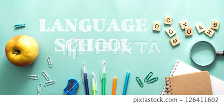 A green background with a bunch of school supplies and an apple 126411602