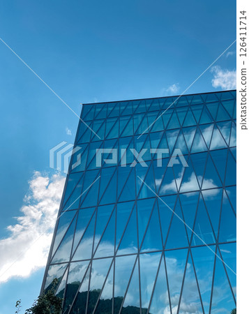 Tall building with a lot of windows and a blue sky in the background Tall building with a lot of windows and a blue sky in the background 126411714