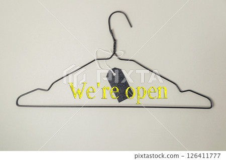 Clothes hanger with a tag on it that says We're open Clothes hanger with a tag on it that says We're open 126411777