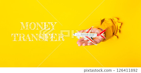 Hand holding a toy airplane with the words money transfer written below it Hand holding a toy airplane with the words money transfer written below it 126411892