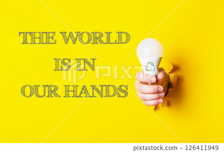 Person holding a light bulb with the words the world is in our hands 126411949
