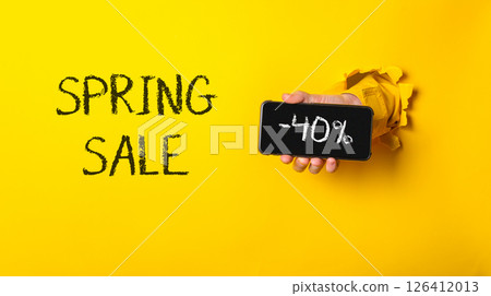 A person holding a cell phone with the words Spring Sale written on it 126412013