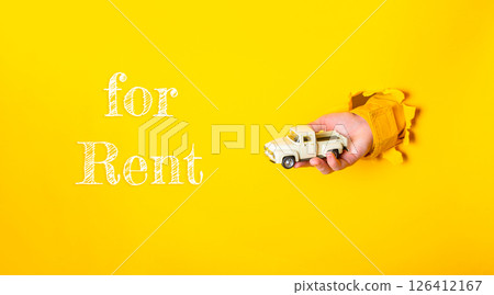 Hand holding a toy truck with the words for rent written underneath 126412167