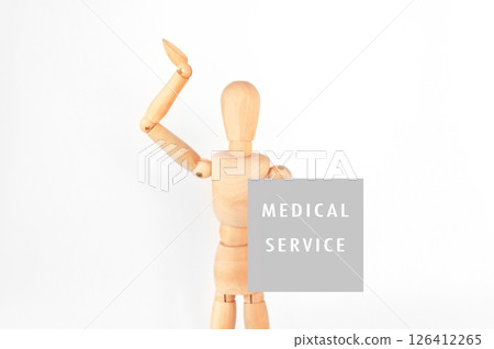 Wooden figure is holding a sign that says Medical Service 126412265