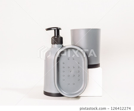 Set of bathroom accessories including a soap dispenser, a soap dish, and a cup 126412274
