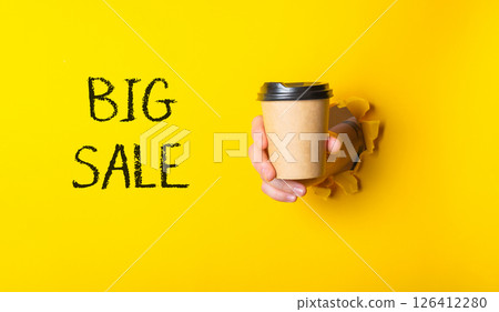 A person is holding a coffee cup with the words Big Sale written on it A person is holding a coffee cup with the words Big Sale written on it 126412280