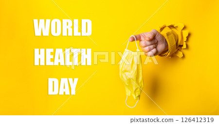 Person holding a yellow mask with the words World Health Day written below 126412319