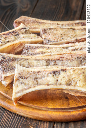Rustic roasted marrow bones rest on warm wooden board, savory richness revealed Rustic roasted marrow bones rest on warm wooden board, savory richness revealed 126412322