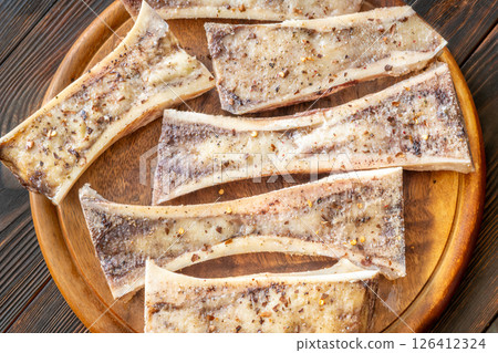 Rustic roasted marrow bones rest on warm wooden board, savory richness revealed 126412324