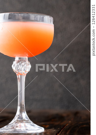 Guayaba Arabica cocktail blends guava, coffee, and rum in moody coupe glass 126412331