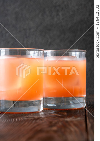 Two guava margaritas glow against rich dark cocktail backdrop Two guava margaritas glow against rich dark cocktail backdrop 126412332