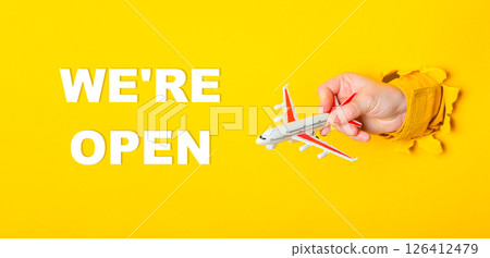 Hand holding a toy airplane in front of a yellow background Hand holding a toy airplane in front of a yellow background 126412479