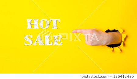 Hand pointing to the word hot sale on a yellow background Hand pointing to the word hot sale on a yellow background 126412480