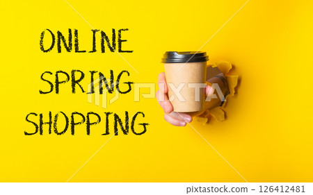 Person holding a coffee cup with the words online spring shopping written in Person holding a coffee cup with the words online spring shopping written in 126412481