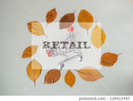 Shopping cart is surrounded by leaves and the word Retail is written above it Shopping cart is surrounded by leaves and the word Retail is written above it 126412497