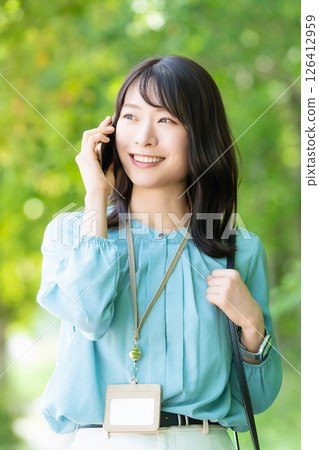 Smiling woman/businesswoman talking on her smartphone while walking along the promenade 126412959