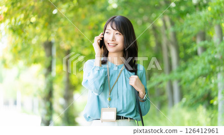 微笑的女人/女商人在海濱長廊散步時用智慧型手機聊天 126412961