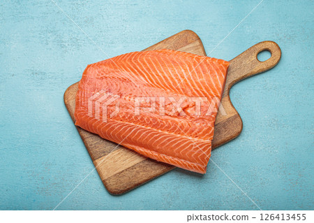 Fresh raw salmon fillet lying on wooden cutting board 126413455