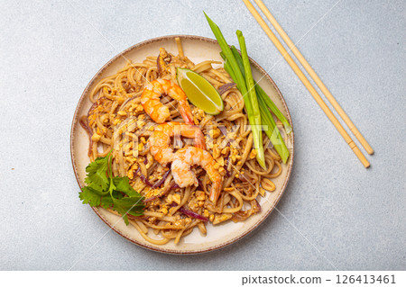 Traditional dish of Thailand, Pad Thai noodles with shrimps and peanuts on a plate top view. South Asian cuisine Traditional dish of Thailand, Pad Thai noodles with shrimps and peanuts on a plate top view. South Asian cuisine 126413461