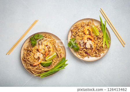 Traditional dish of Thailand, two bowls with Pad Thai noodles with shrimps and peanuts on a plate top view. South Asian cuisine Traditional dish of Thailand, two bowls with Pad Thai noodles with shrimps and peanuts on a plate top view. South Asian cuisine 126413462