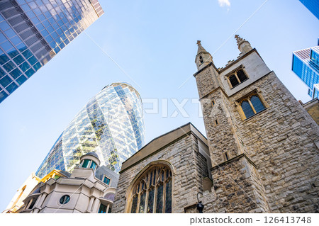 Old St Andrew Undershaft Church stands tall alongside the modern Gherkin building, showcasing a striking contrast of historic and contemporary architecture in London's financial district. 126413748