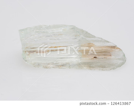 A Roughly Cut Pale Green Beryl Crystal Specimen Exhibiting Schiller Effect, with Visible Inclusions and Parallel Striations, Against a Neutral Light Gray Background A Roughly Cut Pale Green Beryl Crystal Specimen Exhibiting Schiller Effect, with Visible Inclusions and Parallel Striations, Against a Neutral Light Gray Background 126413867
