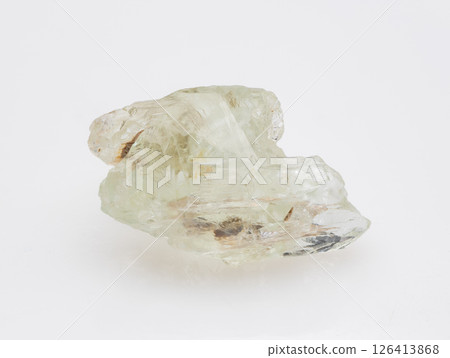 A raw, uncut specimen of pale green beryl crystal showcased against a clean, neutral background, highlighting its natural formations and internal inclusions mineralogy, geology, transparency 126413868