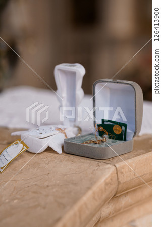 Elegant wedding rings presented in open velvet boxes resting on a decorative marble surface alongside delicate white lace fabric, symbolizing love and commitment 126413900