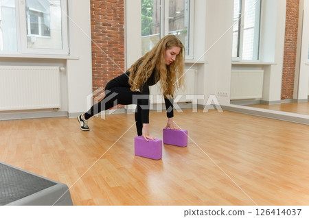 Young woman stretching with yoga blocks indoors. Young woman stretching with yoga blocks indoors. 126414037