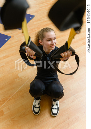 Young woman training with trx fitness straps in the gym. Young woman training with trx fitness straps in the gym. 126414043