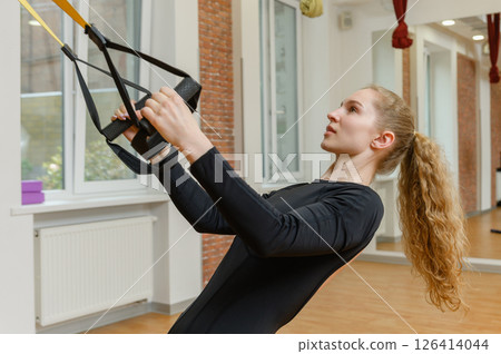 Young woman training with trx fitness straps in the gym. Young woman training with trx fitness straps in the gym. 126414044