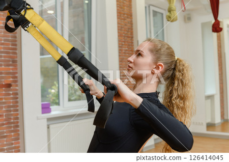 Young woman training with trx fitness straps in the gym. Young woman training with trx fitness straps in the gym. 126414045