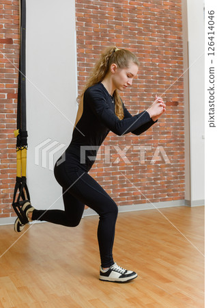 Fit woman doing suspension lunge exercise in gym. Fit woman doing suspension lunge exercise in gym. 126414046