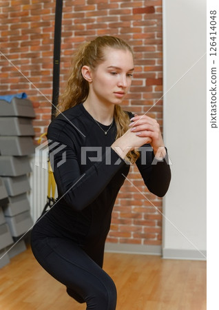 Fit woman doing suspension lunge exercise in gym. 126414048